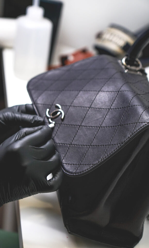 Renowacja torebki Chanel, na zdjęciu widoczny jest proces profesjonalnej renowacji torebki Chanel, czarna torebka w trakcie czyszczenia i przygotowania do renowacji powierzchni