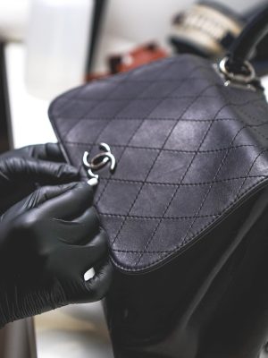 Renowacja torebki Chanel, na zdjęciu widoczny jest proces profesjonalnej renowacji torebki Chanel, czarna torebka w trakcie czyszczenia i przygotowania do renowacji powierzchni